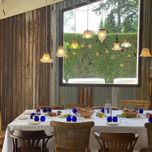 Photo of the tasting room in which you can see the table set, with the glasses for the official Oil Tasting, the lampshades that illuminate the table and the window overlooking the gardens